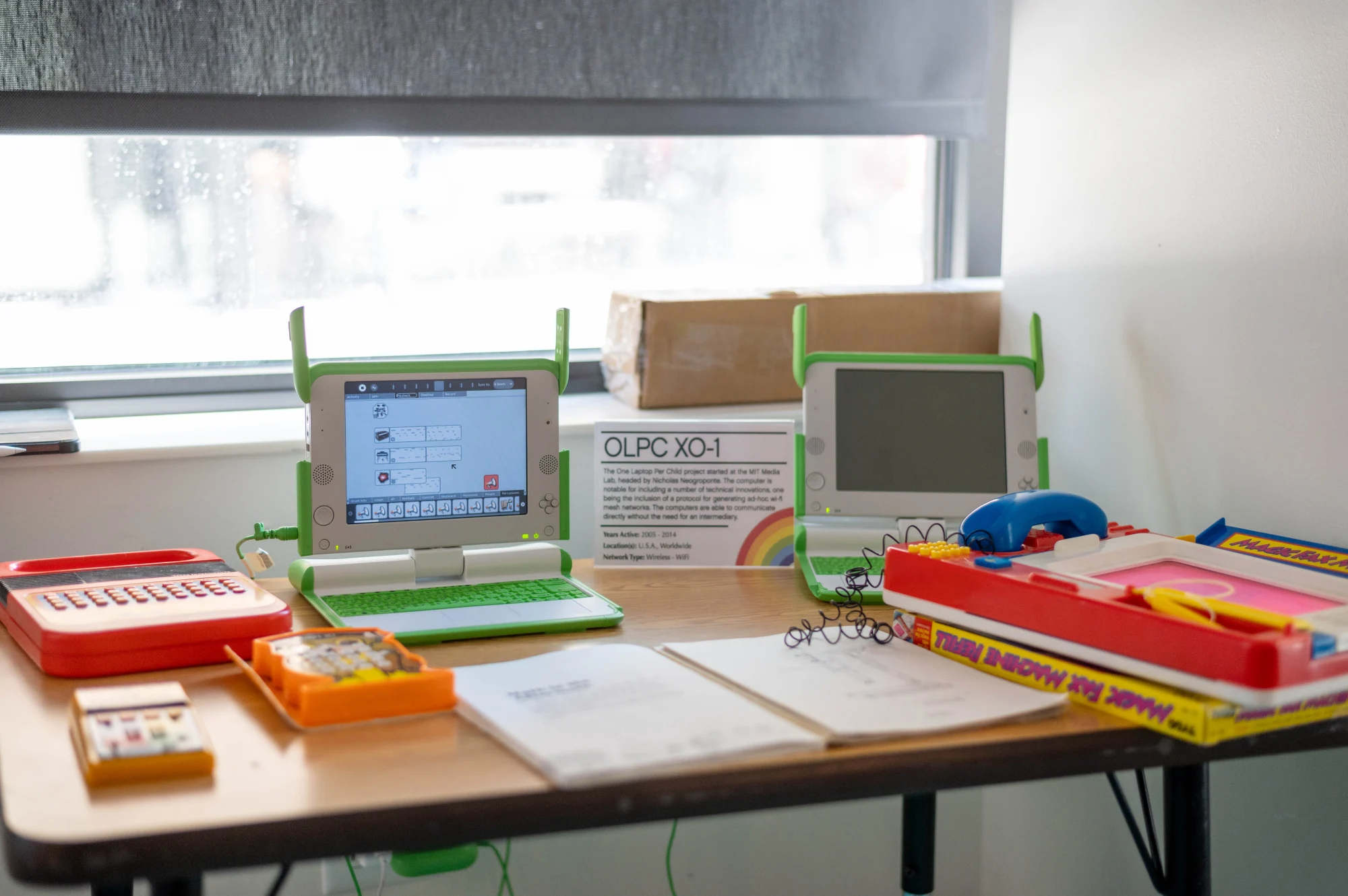 Two OLPC Computers on a table with other kid's tech toys